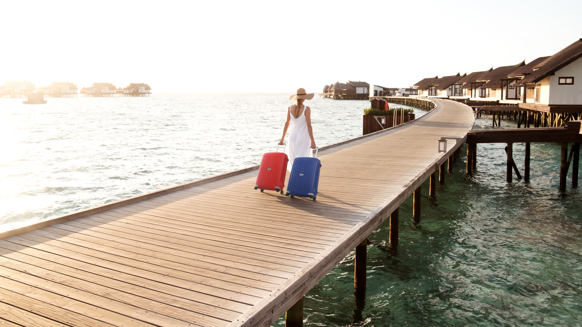 Woman with a blue and red suitcases Samsonite in Maldivas