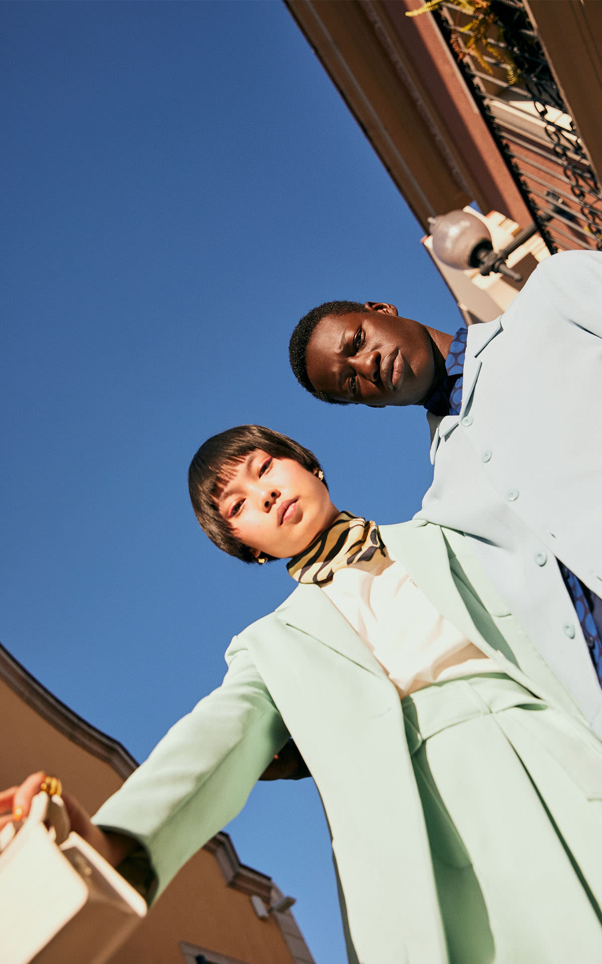 two-models-wearing-pastel-suits-looking-down-at-camera