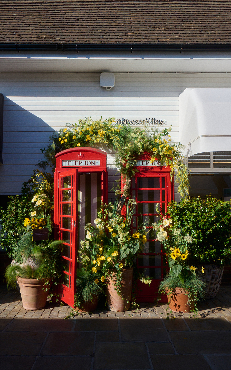 two red phone booths full of flowers at Bicester Village