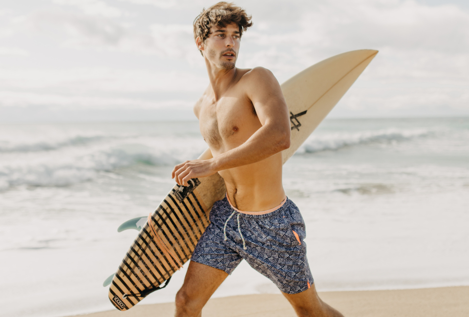 Modelo con un bañador de Saint Tropez azul y una tabla de surf